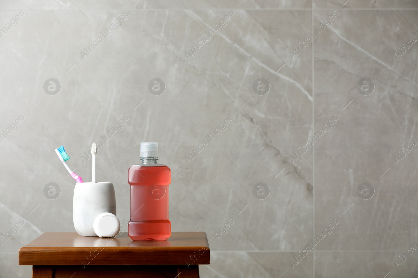 Photo of Bottle of mouthwash, toothbrushes and dental floss on wooden table, space for text