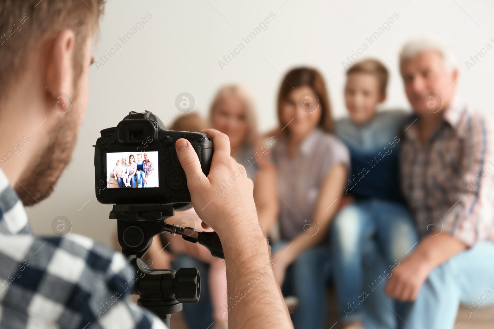 Photo of Professional photographer taking photo of family on sofa in studio