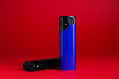 Photo of Stylish small pocket lighters on red background
