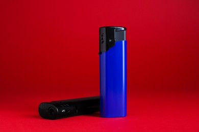 Stylish small pocket lighters on red background