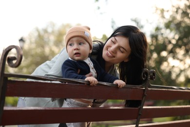 Happy mother and her baby on bench in park