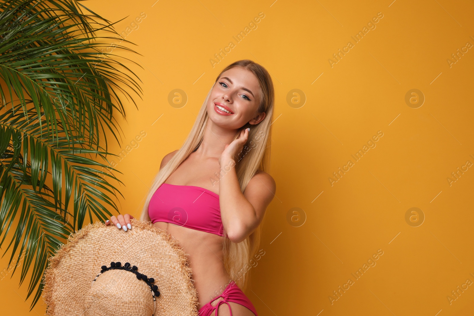 Photo of Pretty young woman wearing stylish bikini on orange background