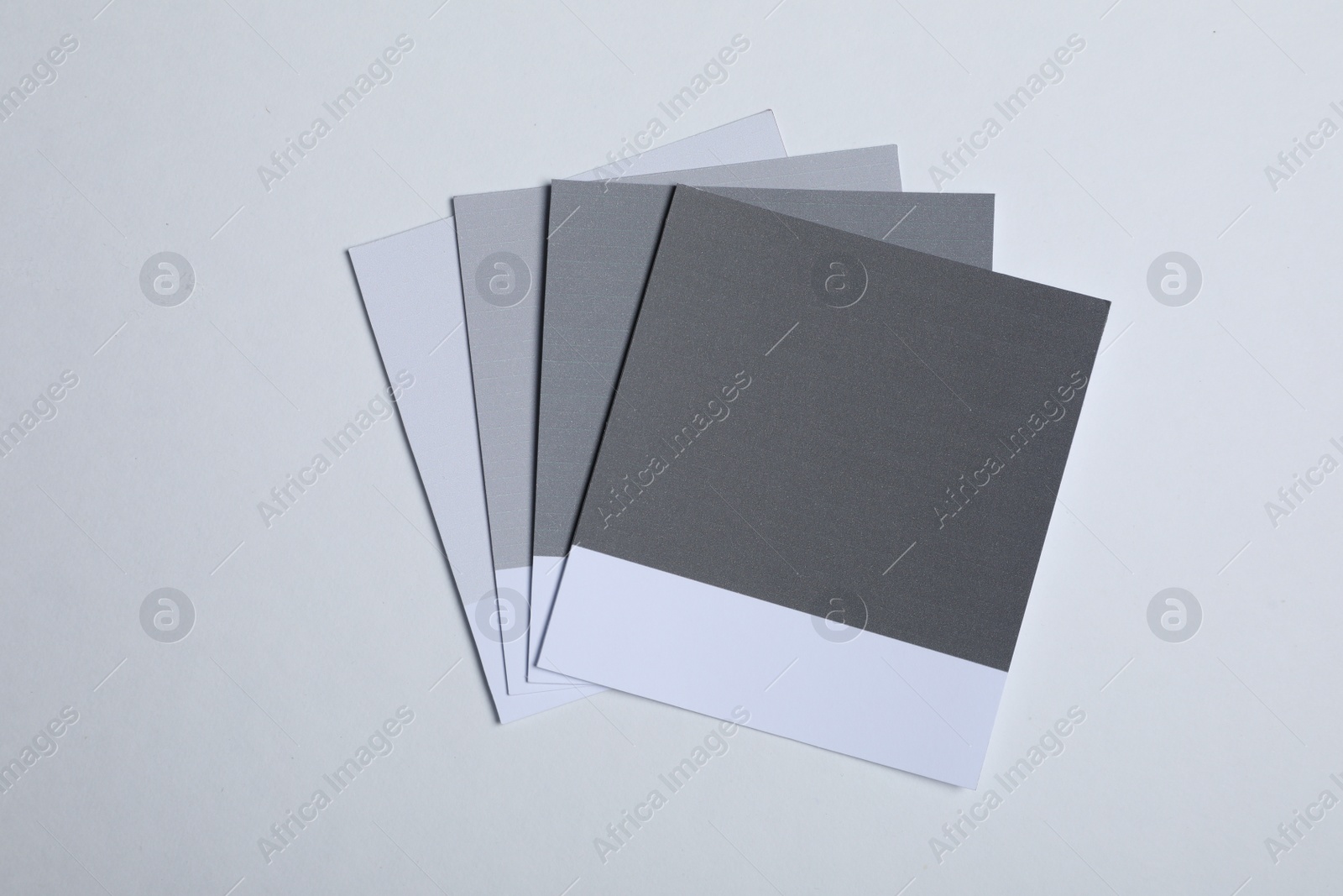 Photo of Color sample cards of grey shades on light background, top view