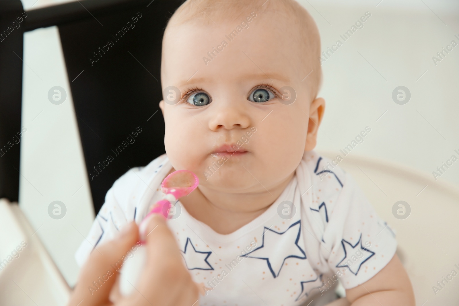 Photo of Mother feeding her cute little baby at home, closeup