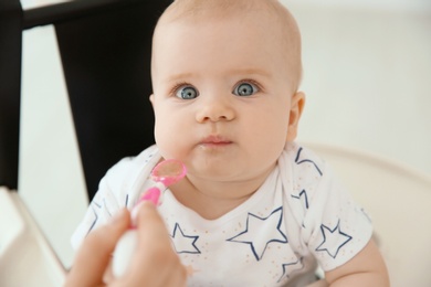 Mother feeding her cute little baby at home, closeup