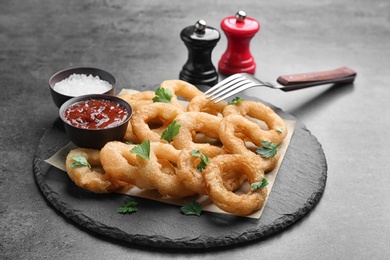 Photo of Fried onion rings served with sauces on slate plate