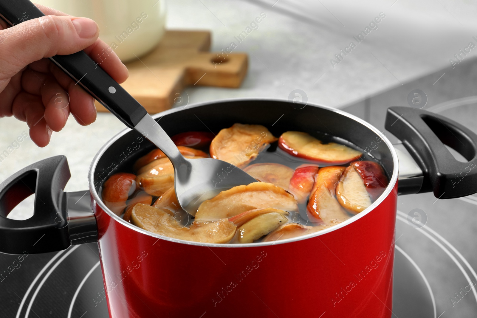 Photo of Woman making delicious compot in pot on stove, closeup