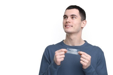 Photo of Young man with whitening strips on light background. Space for text