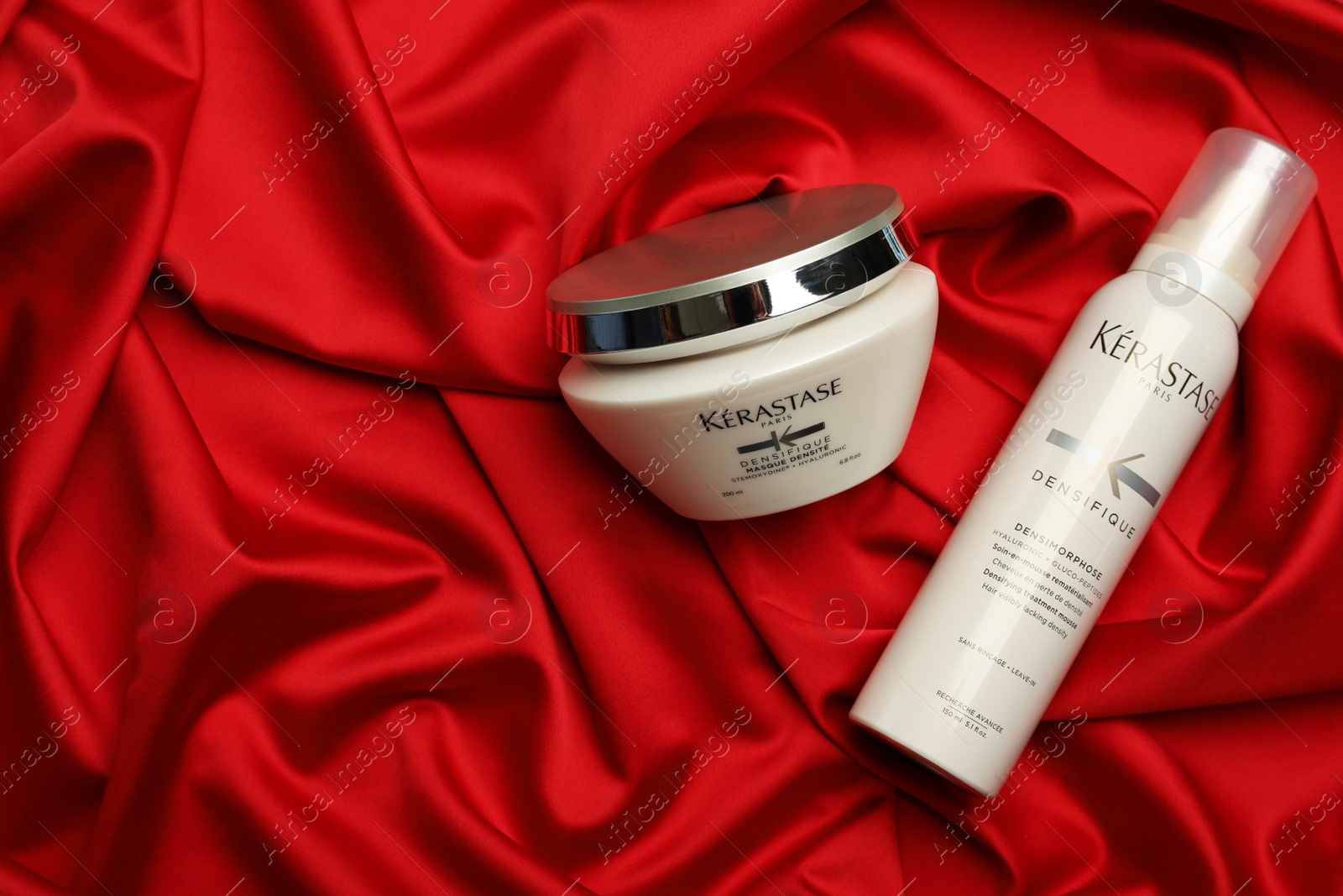 Photo of MYKOLAIV, UKRAINE - SEPTEMBER 08, 2021: Kerastase hair care cosmetic products on red fabric, flat lay. Space for text