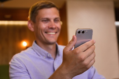 Businessman with smartphone in cafe, focus on hand