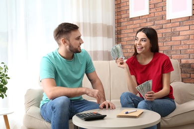 Beautiful young couple with money at home