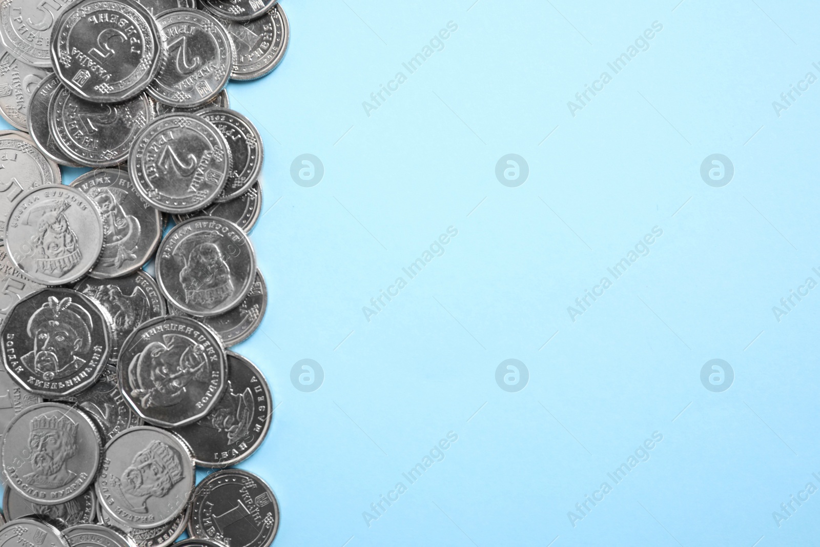 Photo of Ukrainian coins on light blue background, flat lay. Space for text