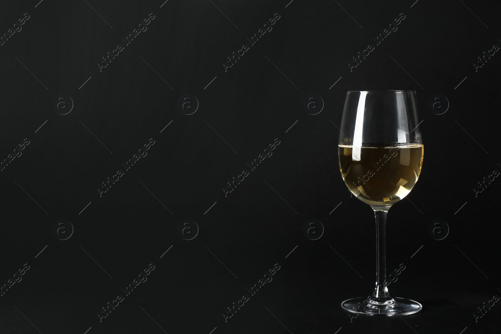 Photo of Glass of expensive white wine on dark background