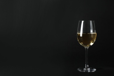 Photo of Glass of expensive white wine on dark background