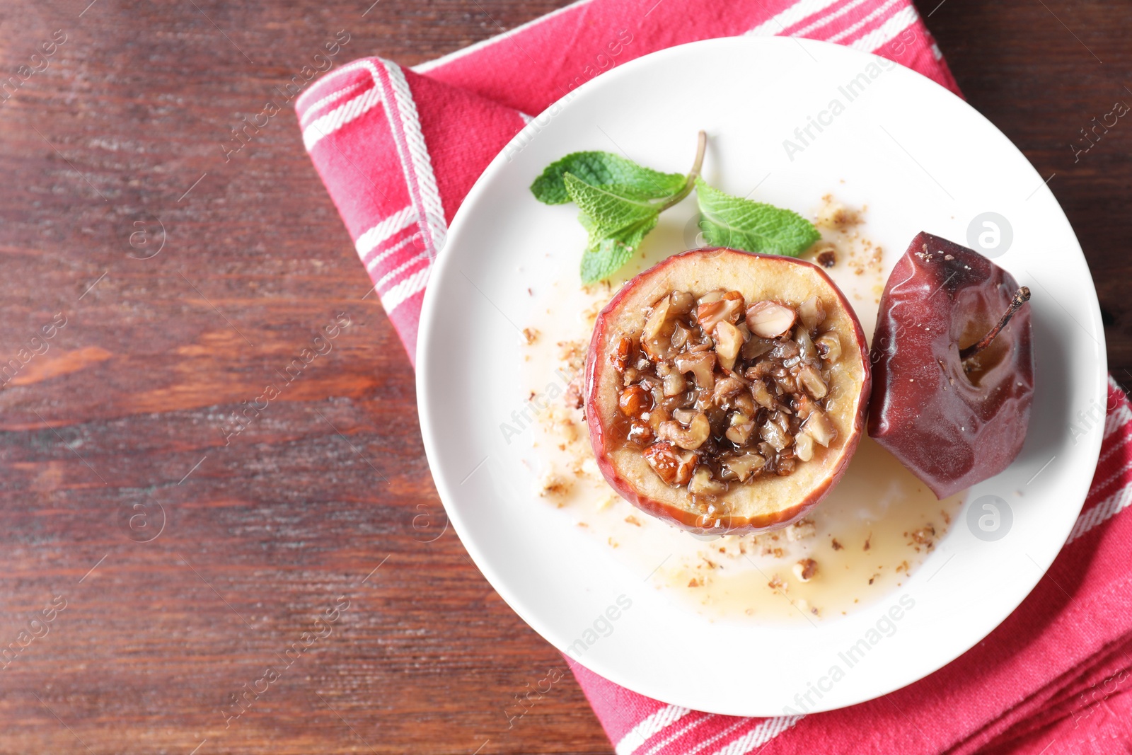 Photo of Tasty baked apple with nuts, honey and mint on wooden table, top view. Space for text