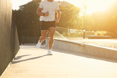 Man running outdoors on sunny day, closeup. Space for text