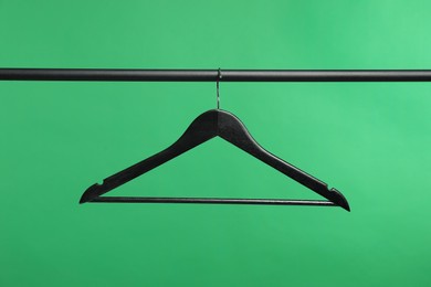 Photo of Empty clothes hanger on rack against green background