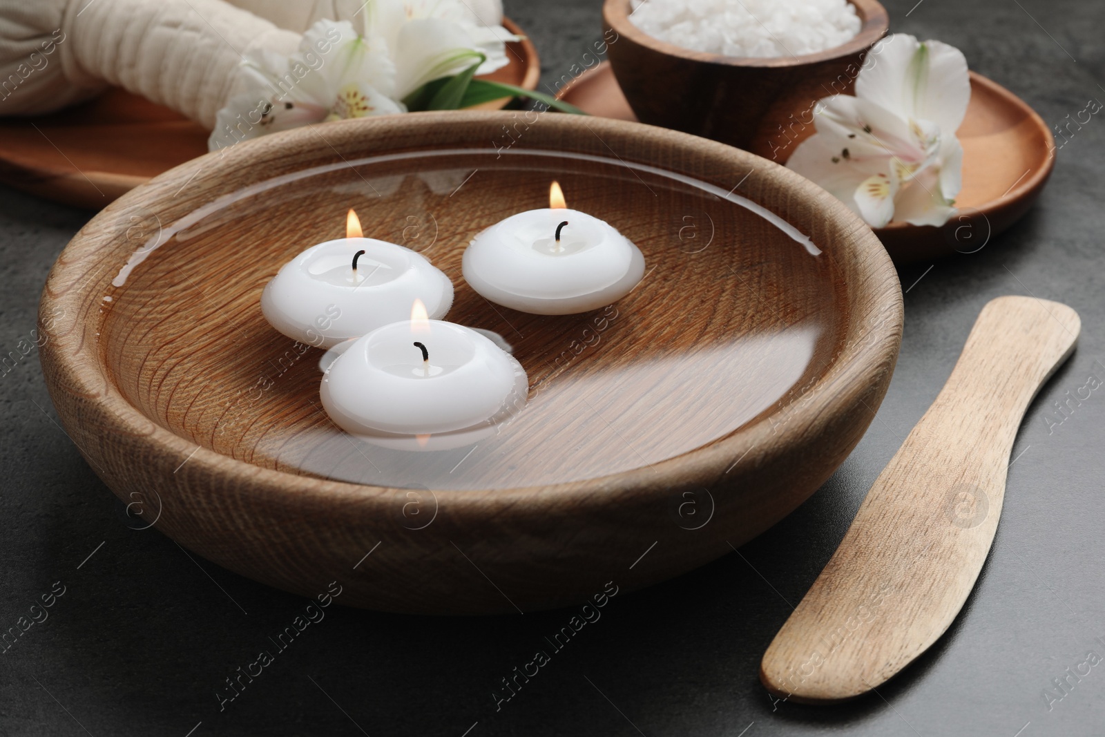 Photo of Spa composition with burning candles in bowl with water on grey table