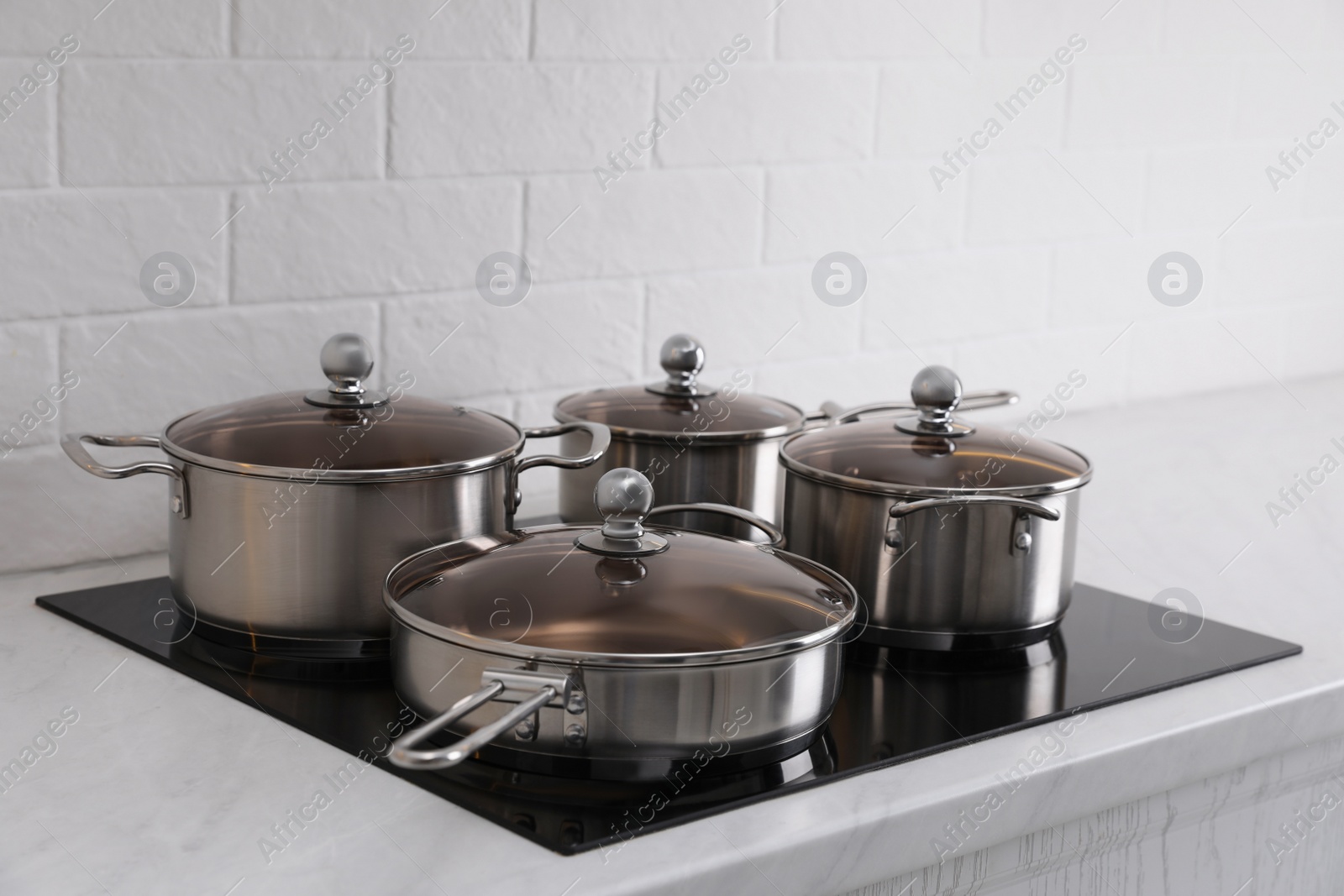 Photo of Set of new clean cookware on cooktop in kitchen