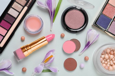 Flat lay composition with eyeshadow palettes and beautiful flowers on white background