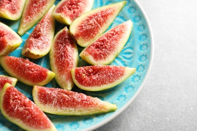 Photo of Plate with fresh ripe fig slices on gray background