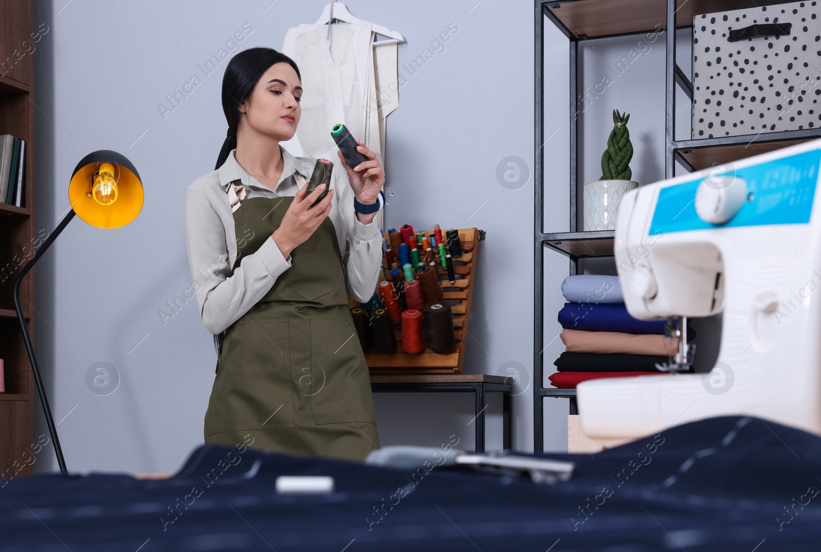 Photo of Dressmaker choosing between color threads in workshop