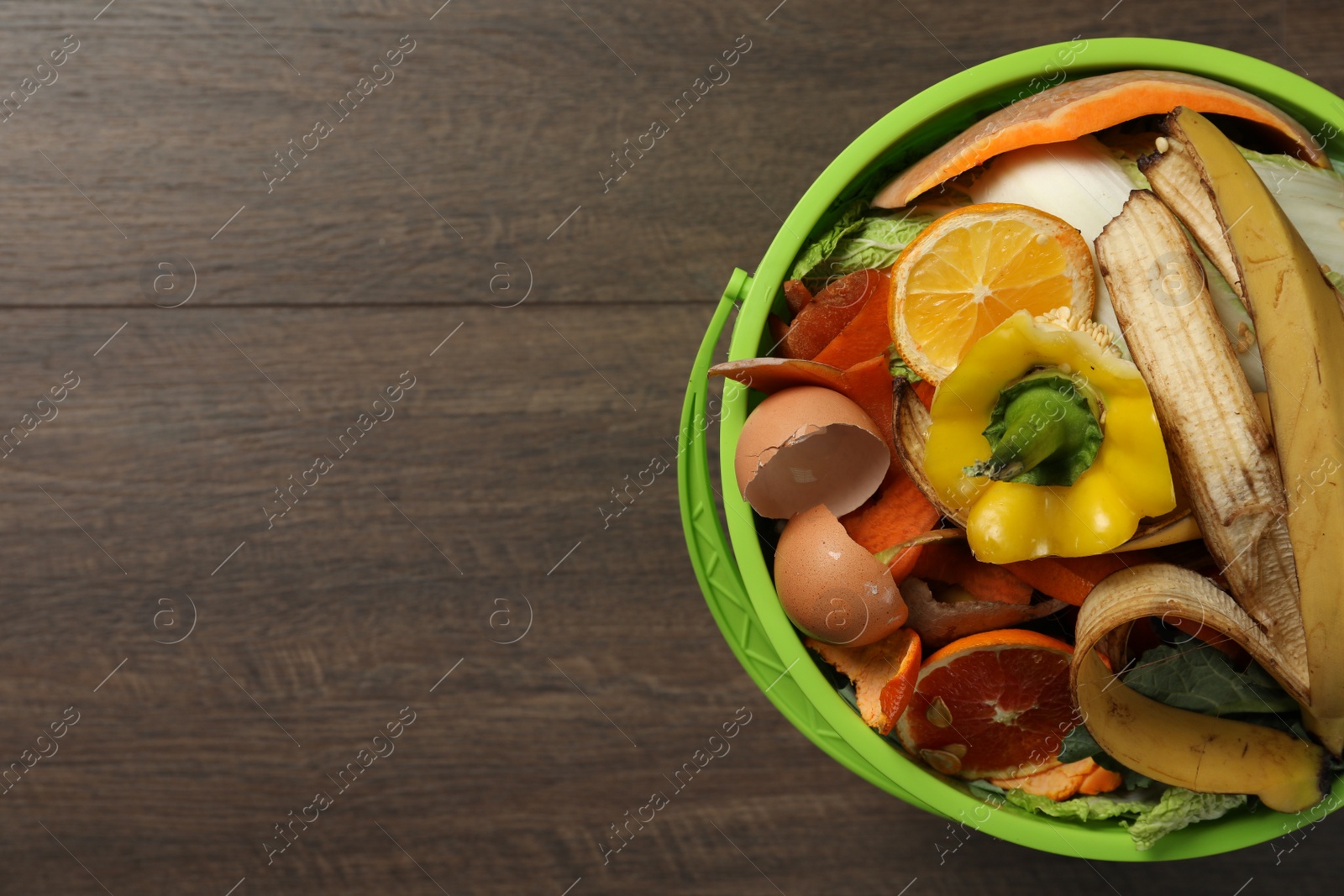 Photo of Natural garbage in trash bin on wooden background, top view with space for text. Composting of organic waste