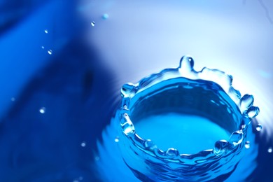 Photo of Splash of clear water with drops on blue background, closeup