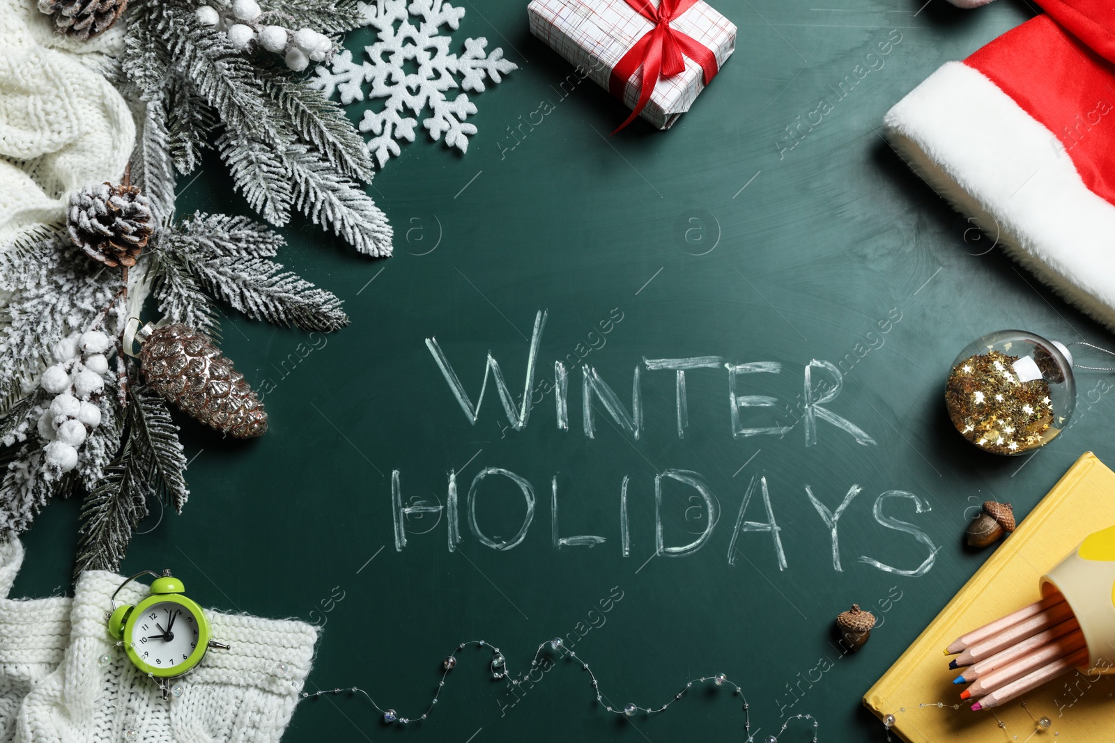 Photo of Flat lay composition of Christmas decorations, school items and alarm clock on blackboard with phrase Winter Holidays