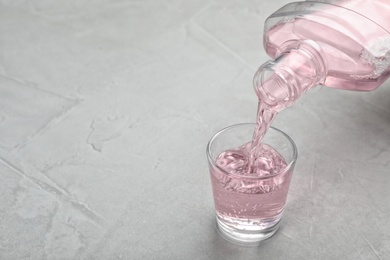 Pouring mouthwash in glass and space for text on light background. Teeth hygiene