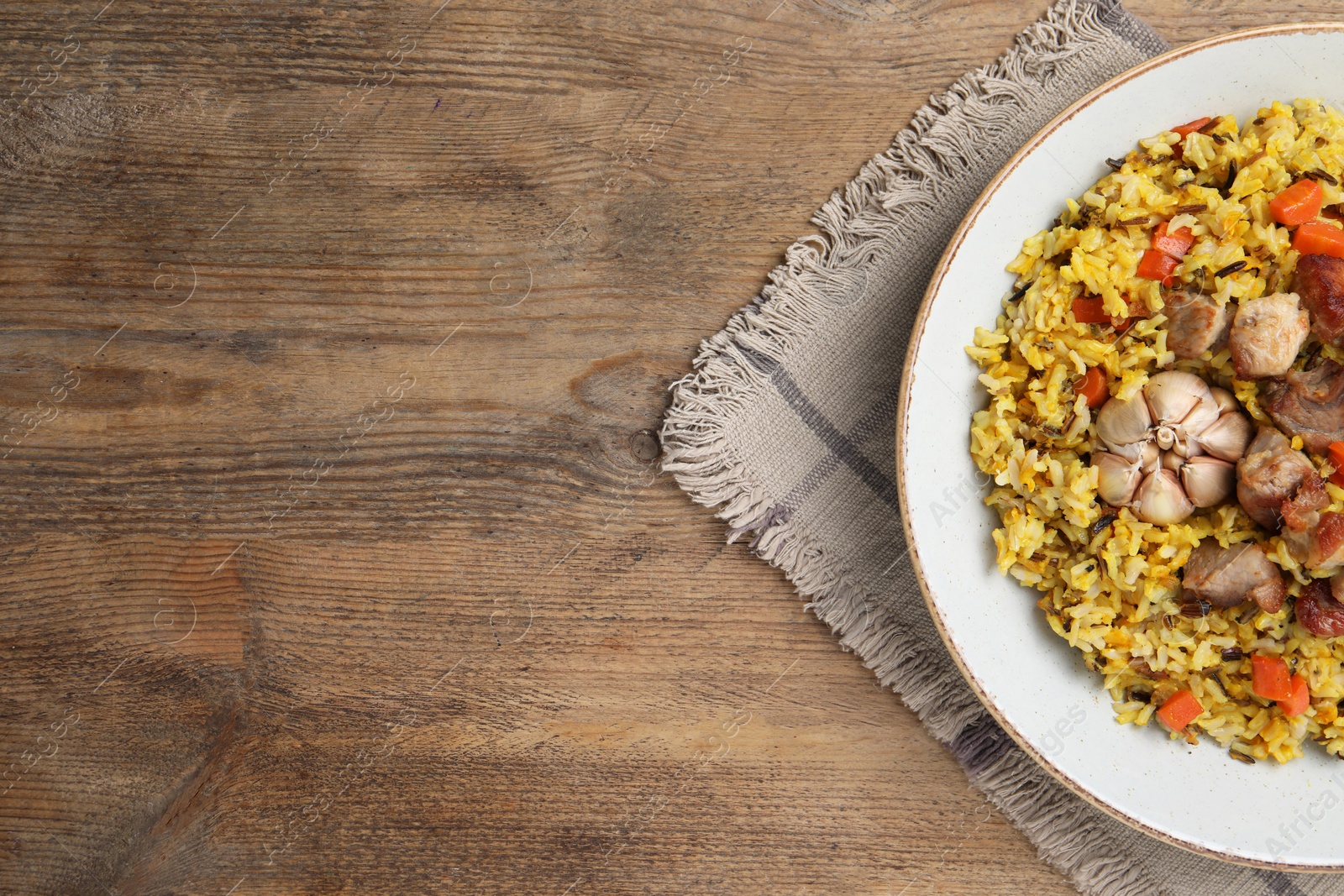 Photo of Delicious pilaf on wooden table, top view. Space for text