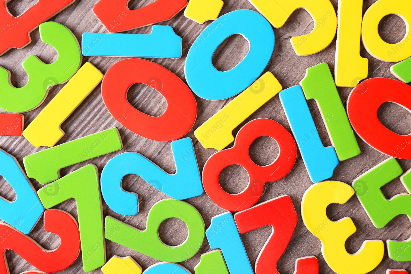 Photo of Colorful numbers on wooden school desk, top view