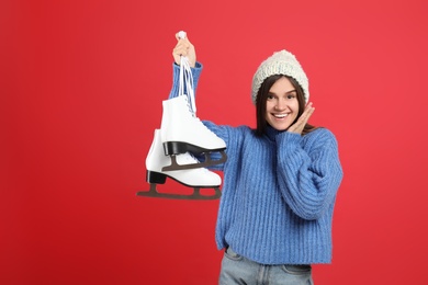 Emotional woman with ice skates on red background