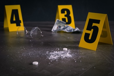 Pill and white powder near crime scene marker on grey stone table, closeup