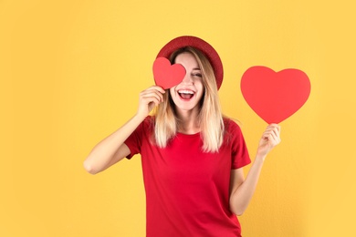 Portrait of young woman with paper hearts on color background