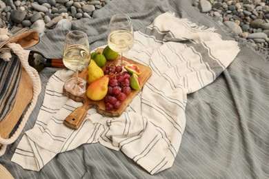 Photo of White wine and fresh fruits on picnic blanket outdoors