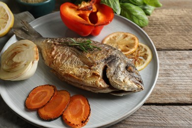 Photo of Delicious dorado fish with vegetables served on wooden table