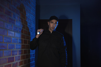 Photo of Male security guard with flashlight in dark corridor