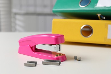 Photo of Stapler and metal staples on white table indoors