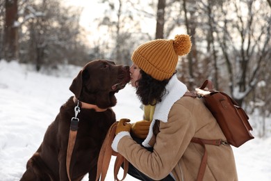 Woman with adorable Labrador Retriever dog in snowy park