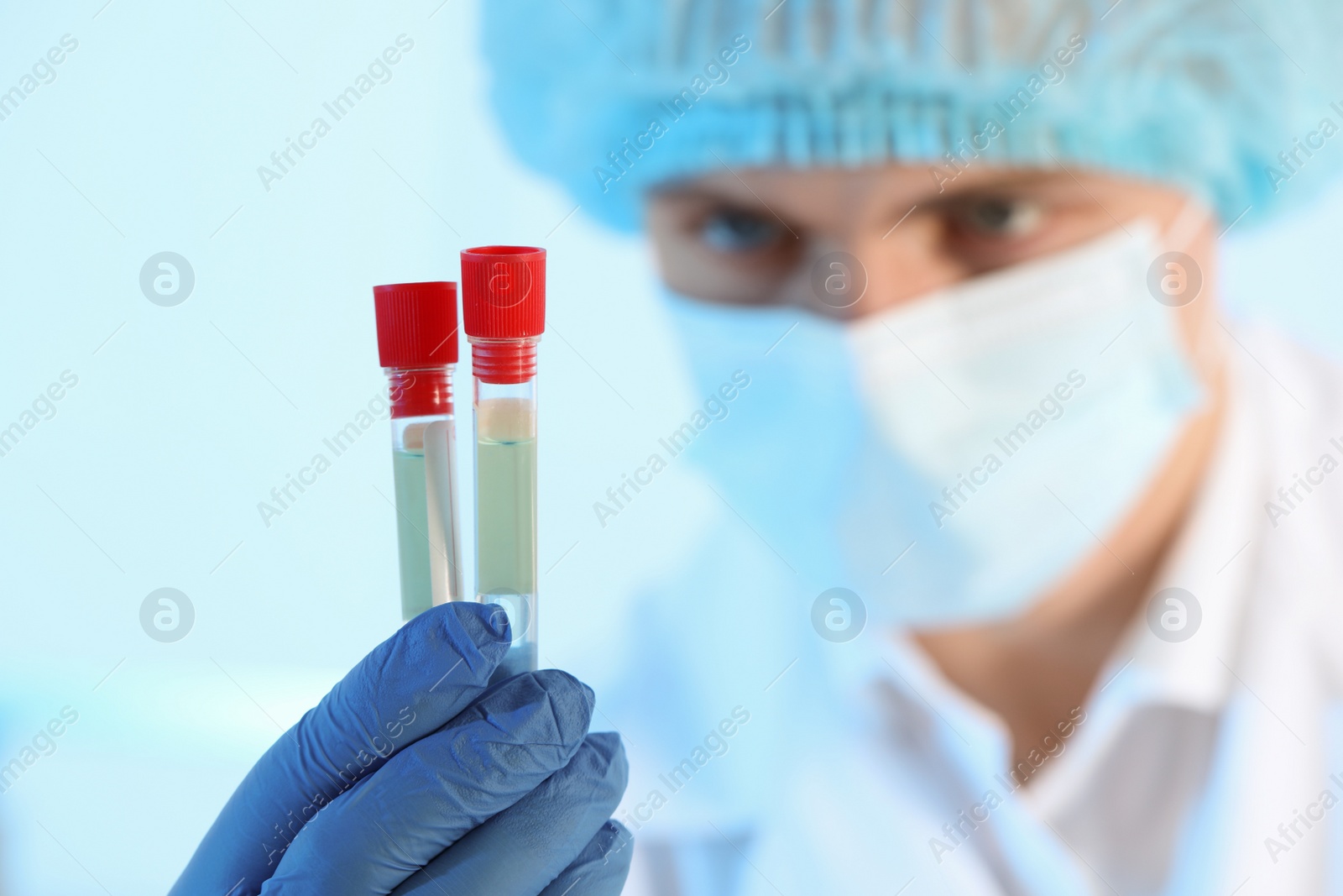 Photo of Scientist working with samples on light blue background, closeup. Medical research