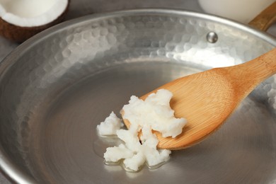 Photo of Frying pan with coconut oil and wooden spatula, closeup. Healthy cooking