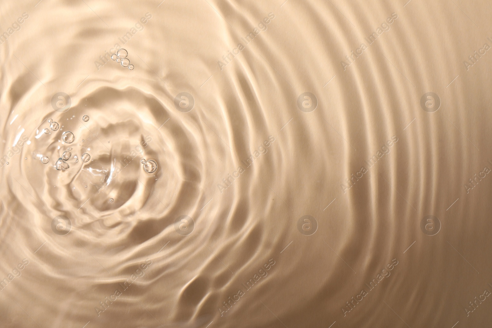 Photo of Closeup view of water with rippled surface on beige background