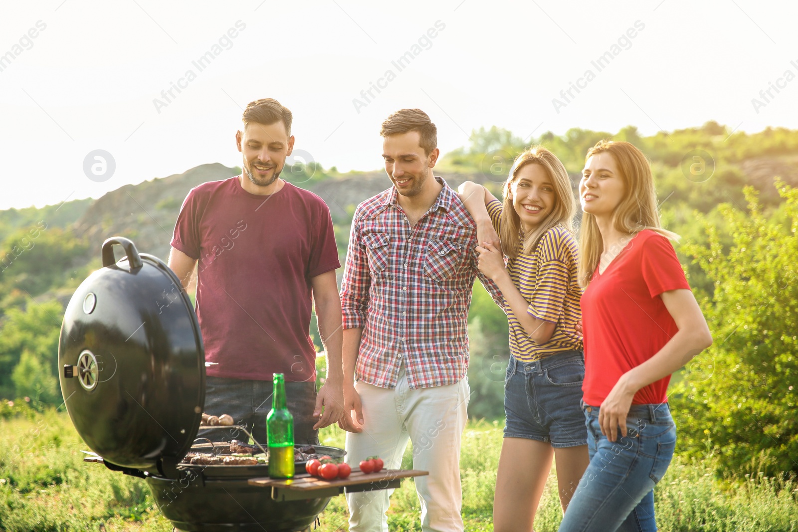 Photo of Young people having barbecue in wilderness. Camping season