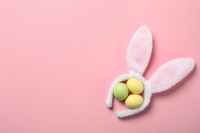 Funny headband with Easter bunny ears and dyed eggs on color background, flat lay. Space for text