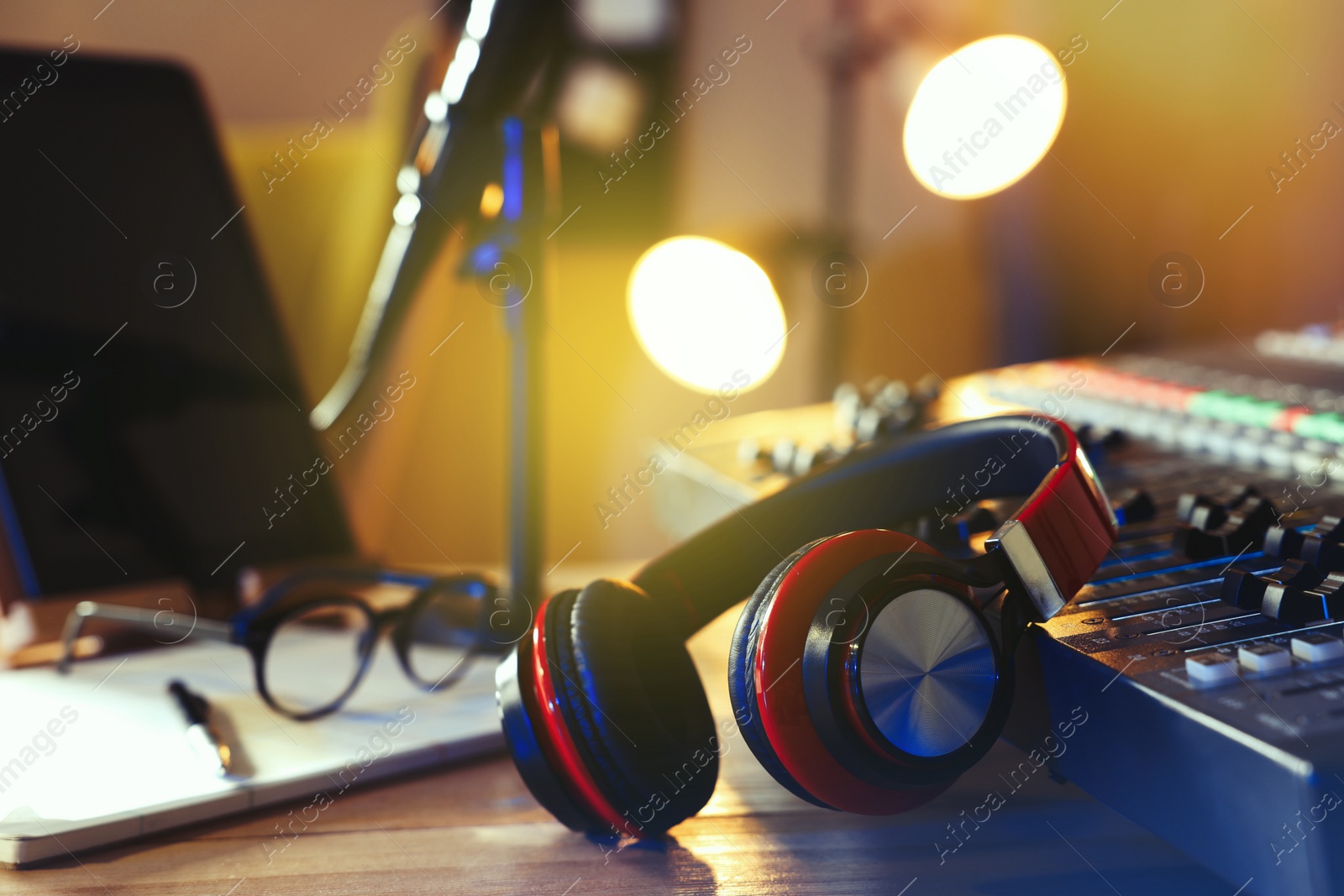 Photo of Headphones near professional mixing console on table in radio studio