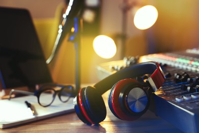 Headphones near professional mixing console on table in radio studio