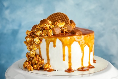 Dessert stand with delicious caramel cake on color background