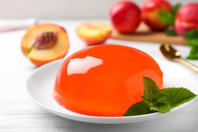 Delicious orange jelly with mint on white wooden table