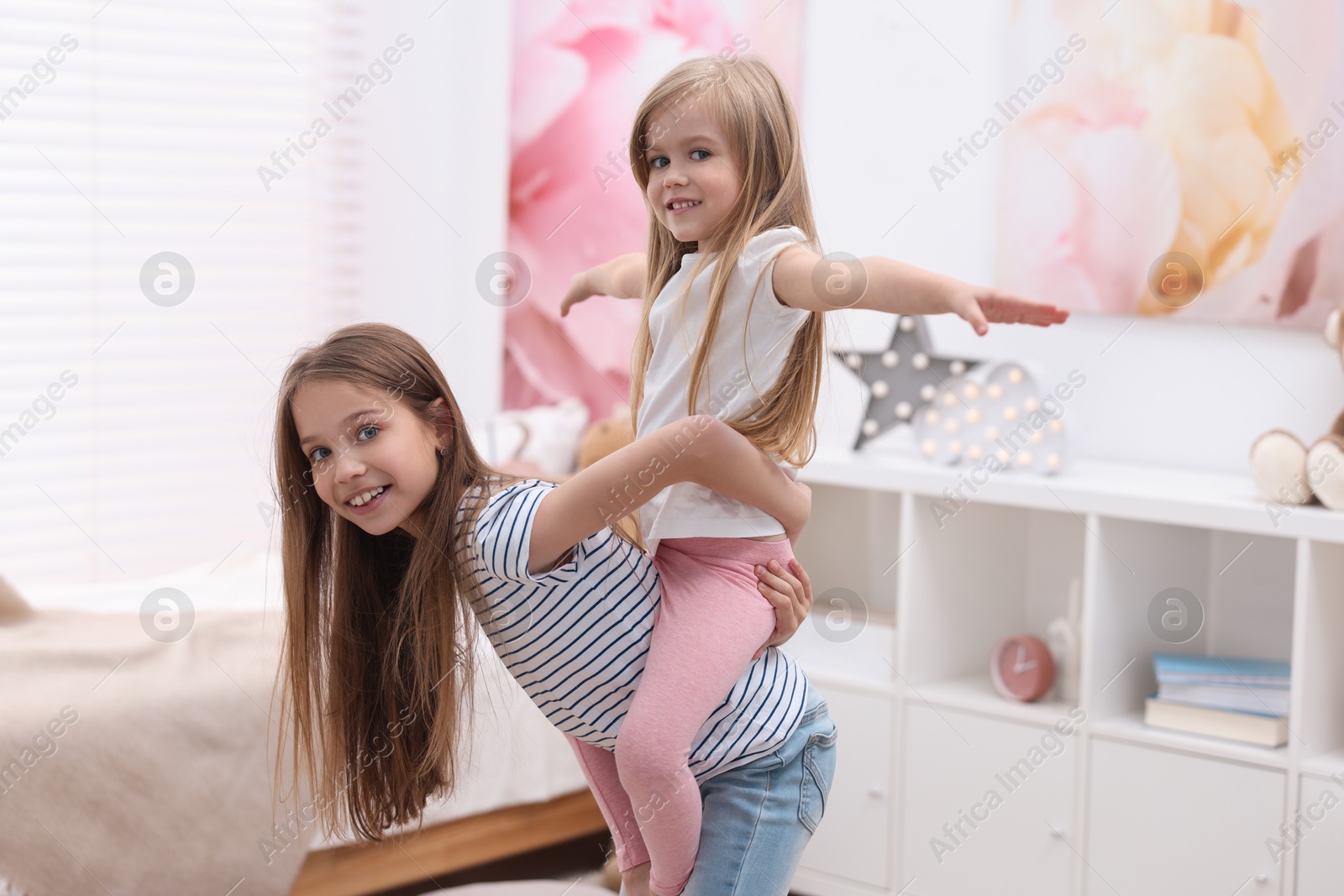 Photo of Cute little sisters having fun together at home